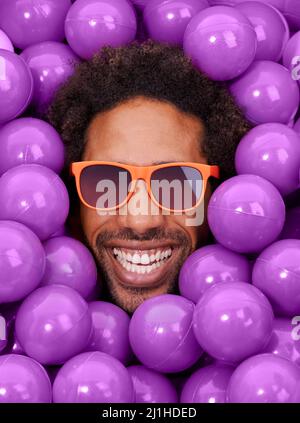 Sieht cool und verrückt aus. Ein junges Gesicht von Schwarzen unter purpurnen Boxenbällen. Stockfoto