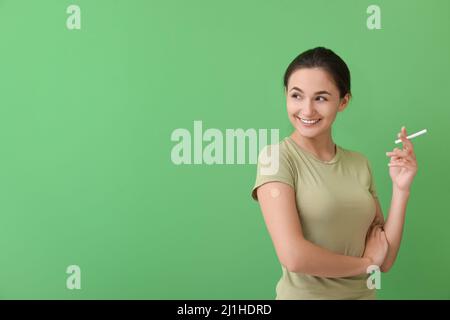 Junge Frau mit aufgetragenen Nikotinpflaster und Zigarette auf farbigem Hintergrund. Raucherentwöhnung Stockfoto