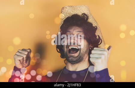 Porträt eines amüsiert aufgeregt Mann in einem lila Hemd stehen und zeigen zwei Finger nach oben auf den Kopierraum isoliert auf gelbem Hintergrund mit einem Bokeh ef Stockfoto