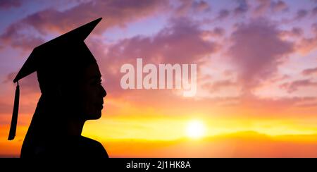 Seitenansicht Silhouette einer Frau mit Hochschulabsolventen im Abendhimmel Stockfoto