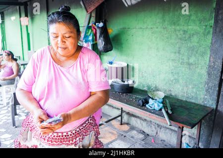 Ältere nicaraguanische Frau, die nach dem Verkauf traditioneller Lebensmittel Geld zählt Stockfoto