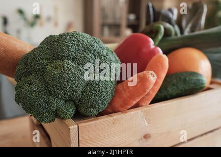 Nahaufnahme von frischem Gemüse wie Brokkoli, Karotten, Gurken und Paprika in einer Holzkiste Stockfoto