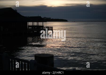 Die Sonne geht in einer Wolke unter und malt Meer und Himmel mit einem reinen Gold Stockfoto