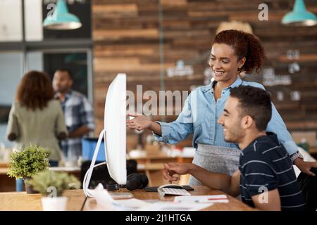 Mit ihrem kreativen Know-how den Weg gehen. Aufnahme von zwei jungen Designern, die in einem Büro an einem Computer arbeiten. Stockfoto