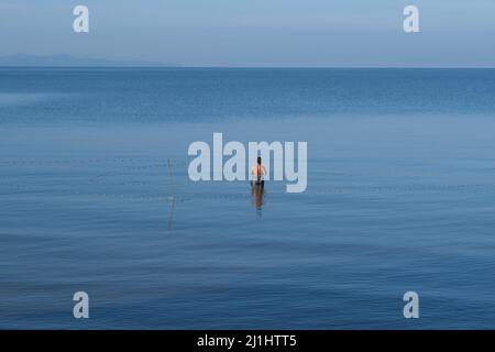 Ein eingeflügeltes Fischernetz steht inmitten eines grenzenlosen blauen Meeres und Himmels Stockfoto