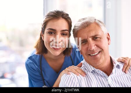 Patienten müssen sich nie mehr Sorgen machen. Porträt eines fröhlichen jungen Arztes und eines reifen männlichen Patienten, der lächelt und in die Kamera schaut. Stockfoto