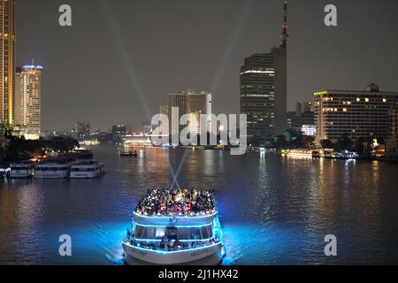 Dutzende von Menschen haben Spaß an Bord eines Flusskreuzfahrtschiffes, das am späten Abend durch Bangkok schwimmt Stockfoto