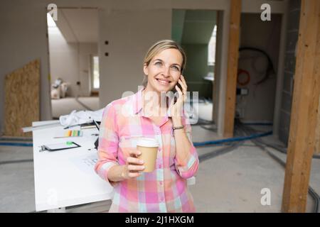 Innenarchitekt mit farbenfroher Bluse arbeitet auf der Baustelle in einem Haus-Loft mit Farbkarten Stockfoto