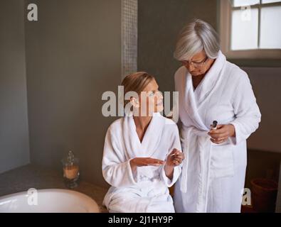 Die Braut auf ihren großen Tag vorbereiten. Aufnahme einer jungen Frau, die ihre Nägel malt, während ihre Großmutter dabei steht. Stockfoto