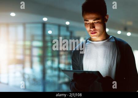 HES ein engagierter Programmierer. Aufnahme eines hübschen jungen männlichen Programmierers, der spät in seinem Büro arbeitet. Stockfoto