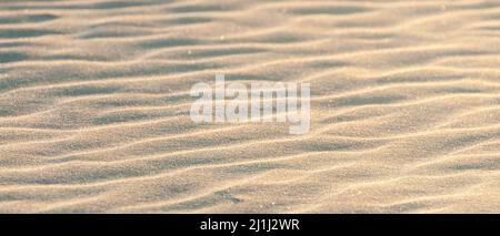 Banner einer pastellfarbenen Textur aus feinem Sand am Strand, der am Abend Wellen bildet Stockfoto