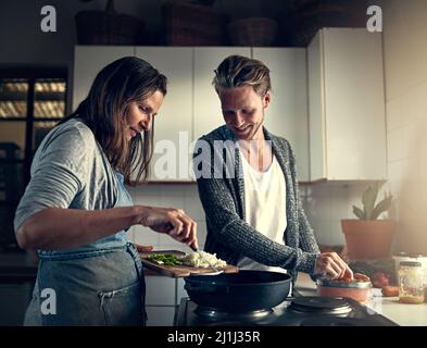 Etwas Besonderes zubereiten. Aufnahme einer Mutter und ihres erwachsenen Sohnes, die zu Hause in ihrer Küche kochen. Stockfoto
