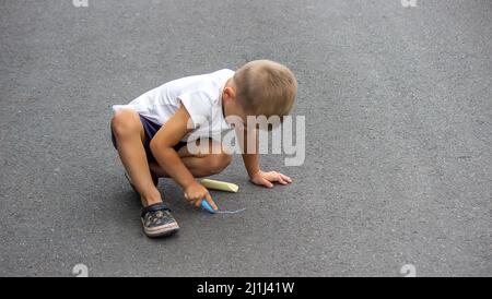 Das Kind zeichnet mit Kreide auf dem Bürgersteig. Selektiver Fokus Stockfoto