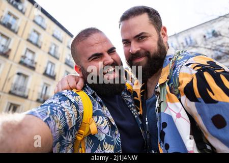 Junge glücklich Gay Paar nimmt ein Selbstporträt zusammen im Freien. Sie lächeln und tragen Sommerkleidung. Stockfoto