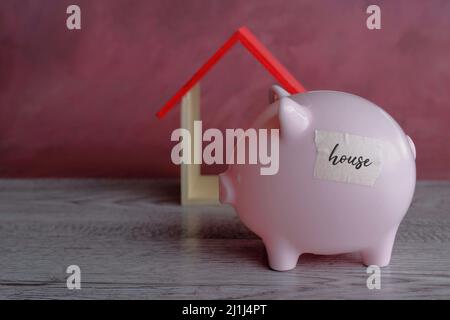 Sparschwein und Holzhaus, Platz für Text kopieren. Immobilien, Finanzplanung, Sparkonzept Stockfoto