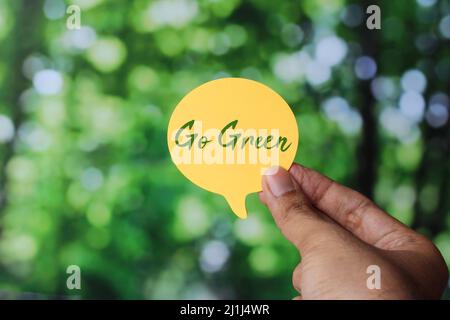 Hand halten Sprechblase mit Text Go Green auf Natur Bokeh Hintergrund. Tag der Erde, rette den Planeten Stockfoto