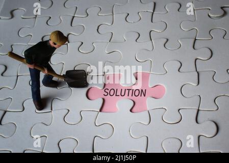 Miniatur-Mann und fehlende Puzzle mit Text-LÖSUNG. Suche nach Lösungskonzept. Stockfoto