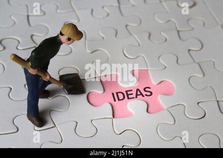 Miniatur-Mann und fehlende Puzzle mit Text-IDEEN. Auf der Suche nach Ideen Konzept. Stockfoto