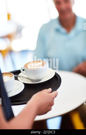 Mit Kaffee wird alles besser. Kurzer Schuss einer Kellnerin mit zwei Kaffees. Stockfoto