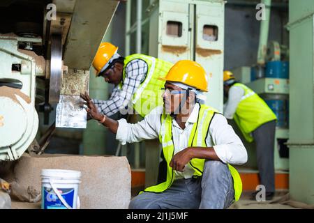 Industriearbeiter arbeiten an Maschinen mit Schutzhelm in der Fabrik - Konzept der blauen Kragen Arbeitsplätze, Teamarbeit und Beruf Stockfoto