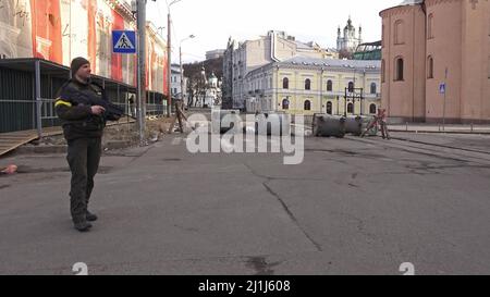 KIEW, UKRAINE 08. März. Ein Mitglied der Zivilverteidigung Kiews steht neben einer Barrikade aus Müllcontainern im historischen Viertel Podil im Bezirk Podilskyi, während Russlands Invasion der Ukraine am 08. März 2022 in Kiew, Ukraine, fortgesetzt wird. Russland begann eine militärische Invasion der Ukraine, nachdem das russische parlament Verträge mit zwei abtrünnigen Regionen in der Ostukraine gebilligt hatte. Es ist der größte militärische Konflikt in Europa seit dem Zweiten Weltkrieg Stockfoto