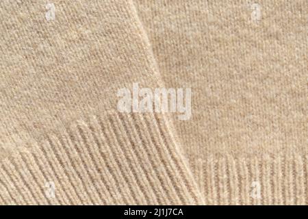 Strickpullover in beige warmer Pastellfarbe mit vertikalem Strick, die Textur ist deutlich sichtbar. Stockfoto