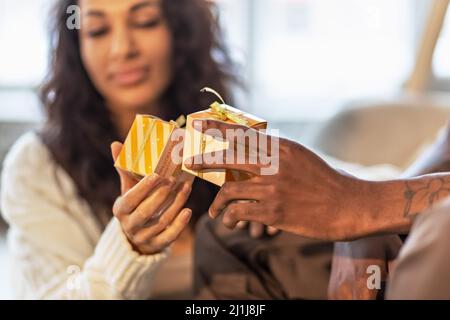 Ein glückliches Paar von Mulattoes tauschen Geschenke miteinander aus. Gemeinsame Familienfeiern Stockfoto