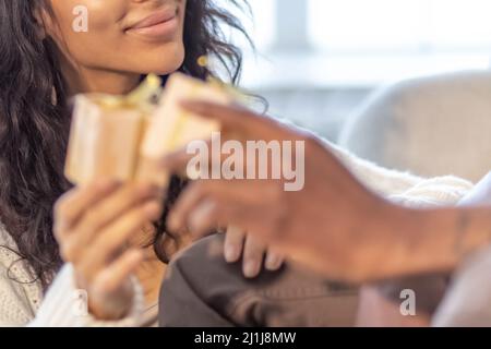 Ein glückliches Paar von Mulattoes tauschen Geschenke miteinander aus. Gemeinsame Familienfeiern Stockfoto