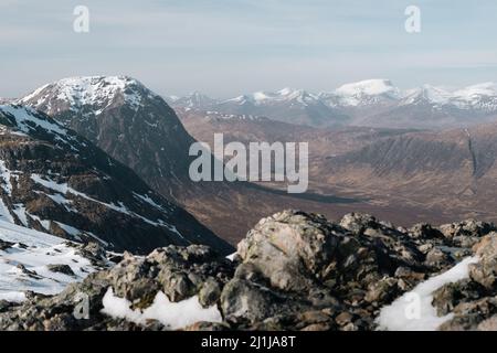 Blick auf Buchaille Etive Mor und Ben Nevis mit schneebedeckten Gipfeln, vom Berg Glencoe aus gesehen Stockfoto