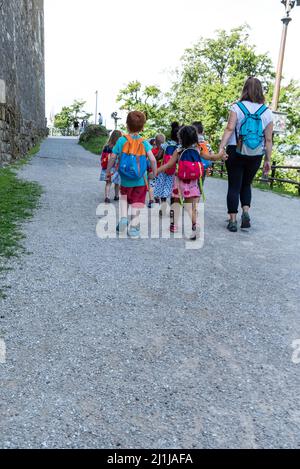 Ljubljana, Slowenien - 15. Juli 2021: Kinder mit Rucksäcken auf einer Schulreise. Kleinkinder halten sich die Hände. Gruppe von Kindern im Vorschulalter. Stockfoto