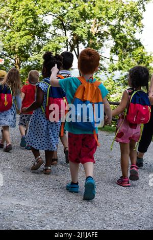 Ljubljana, Slowenien - 15. Juli 2021: Kinder mit Rucksäcken auf einer Schulreise. Kleinkinder halten sich die Hände. Gruppe von Kindern im Vorschulalter. Stockfoto