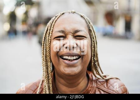 Ältere afrikanische Frau lächelt vor der Kamera mit Stadt im Hintergrund - Fokus auf Mund Stockfoto