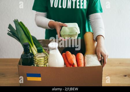 Volunteer bereitet Nahrungsmittelbox für ukrainische Kriegsflüchtlinge vor - Konzentrieren Sie sich auf Packung Hühnereier Stockfoto