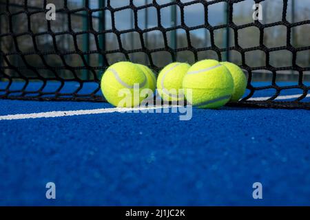 Selektiver Fokus, fünf Kugeln in der Nähe des Netzes eines blauen Paddle-Tennisplatzes Stockfoto