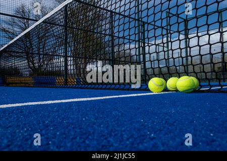 Selektiver Fokus, fünf Kugeln in der Nähe des Netzes eines blauen Paddle-Tennisplatzes Stockfoto