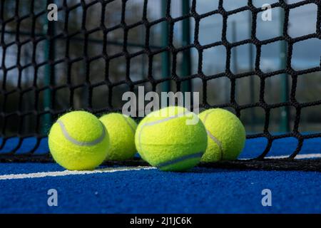 Selektiver Fokus, fünf Kugeln in der Nähe des Netzes eines blauen Paddle-Tennisplatzes Stockfoto