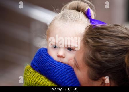 Mädchen in den Armen ihrer Mutter in einem Schal in der Farbe der Flagge der Ukraine. Hochwertige Fotos Stockfoto