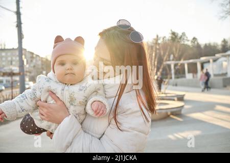 Glückliche harmonische Familie im Freien. Mutter wirft Baby, lachend und spielend im Sommer