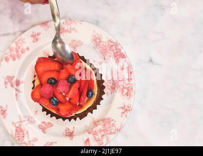 Junge Frau, die Kuchen mit Erdbeertochter verkostet, selektiver Fokus. Stockfoto