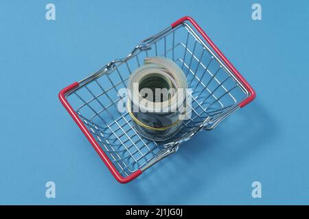 In einen Schlauch gerollte Dollars liegen in einem Einkaufskorb. Stockfoto