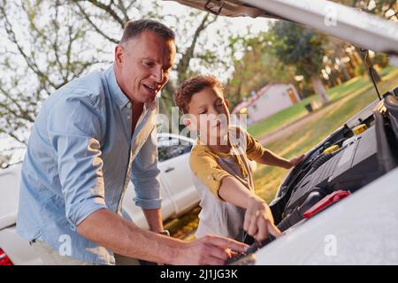 HES lernt schnell. Aufnahme eines Vaters, der seinem jungen Sohn den Motor eines Autos zeigt. Stockfoto