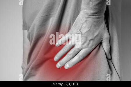 Schmerzen im unteren Rücken. Lumbago. Mann Hände mit roten schmerzhaften Punkt Nahaufnahme. Wirbelsäulenverletzung, gequetschte Muskeln. Gesundheitliche Probleme, Heilung Konzept. Hochwertige Fotos Stockfoto