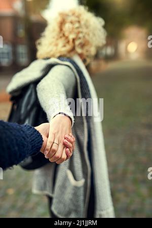 Komm schon, liebe. Rückansicht einer jungen Frau, die ihren Mann durch eine fremde Stadt führt. Stockfoto