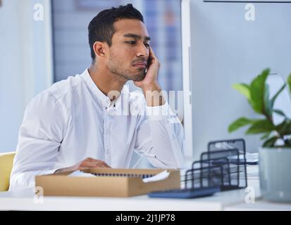 Ich bekomme heute einfach nicht viel zu tun. Eine kurze Aufnahme eines Geschäftsmanns, der gelangweilt aussachte, während er an seinem Schreibtisch saß. Stockfoto