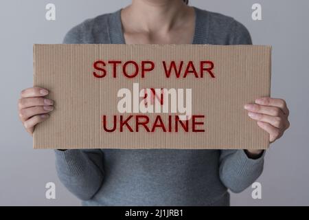 Eine Frau hält ein Papierplakat mit dem Schild „STOP WAR IN DER UKRAINE“ Stockfoto