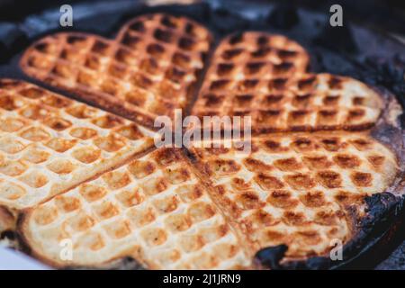 Waffel oder Waffeln in einer Pfanne, Gericht aus gesäuertem Teig oder Teig, der zwischen zwei gemusterten Tellern gekocht wird, aus nächster Nähe Stockfoto