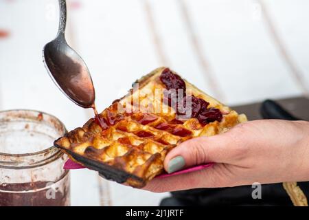 Zubereitung von Waffeln oder Waffeln mit Marmelade, Gericht aus gesäuertem Teig oder Teig, der zwischen zwei gemusterten Tellern gegarten wird Stockfoto