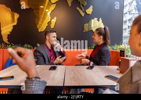 Eine Gruppe von multirassischen Geschäftsleuten lächelt und redet während des Sitzens Stockfoto