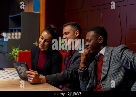 Eine Gruppe von multirassischen Geschäftsleuten lächelt und denkt über die Ergebnisse nach, die sie sehen Stockfoto