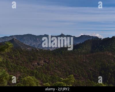 Blick auf die rauen Berge der zentralen Insel Grand Canaria, Spanien vom Tamadaba Naturpark mit dem berühmten Felsen Roque Nublo und Hügeln mit Bäumen. Stockfoto